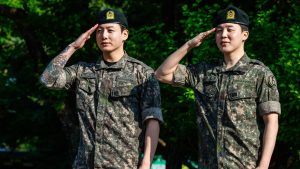 This photo taken on on June 11, 2025 shows Jungkook (L) and Jimin of K-pop supergroup BTS saluting at an outdoor sporting facility in Yeoncheon, shortly after their release from 18 months of South Korean military service.
